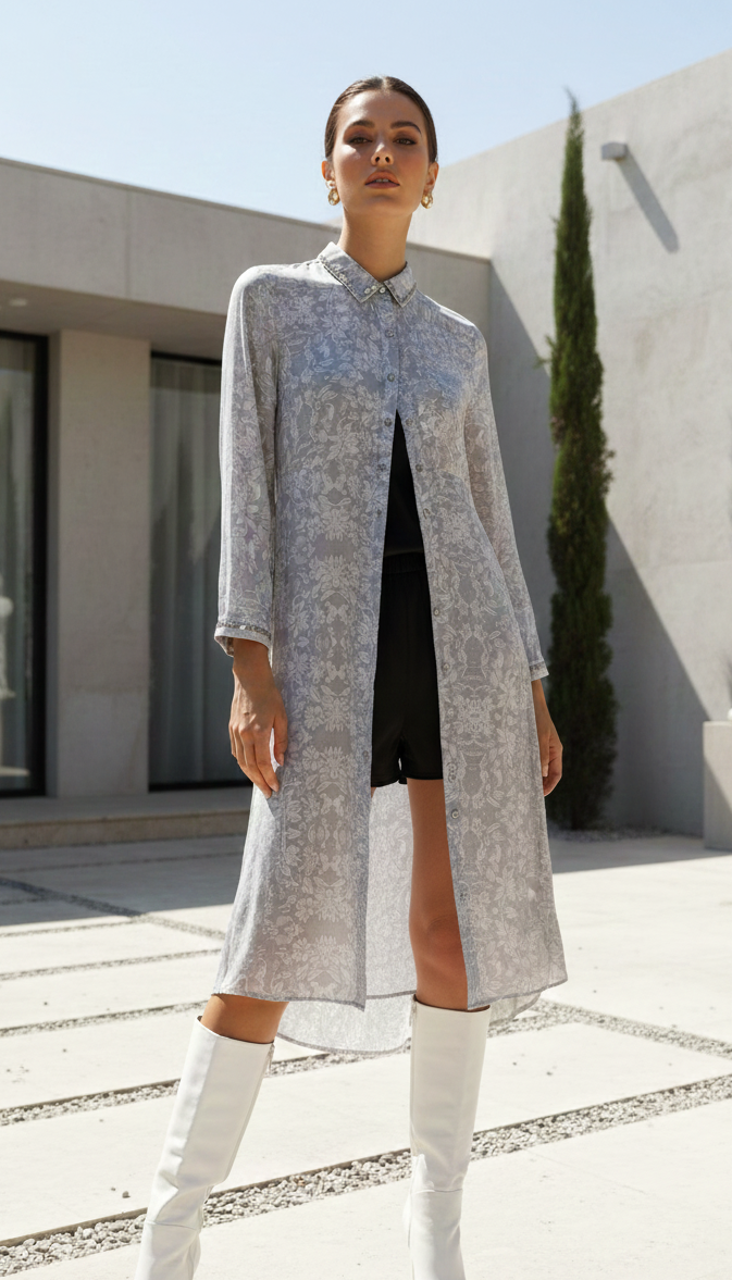 Woman wearing a long, light-colored coat with a patterned collar in an outdoor setting.